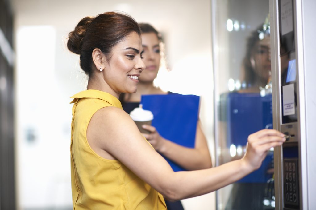 Colleagues using vending machine chatting